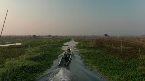 traditional long tail boat travels in small waterway of floating gardens at inle