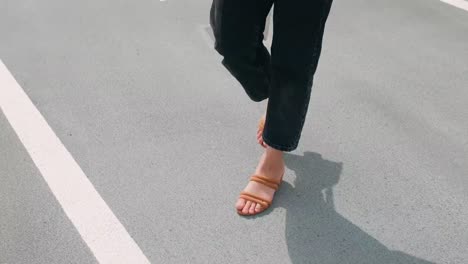 Close-up-of-woman-walking-on-concrete-wearing-small-heels-while-carrying-her-handbag