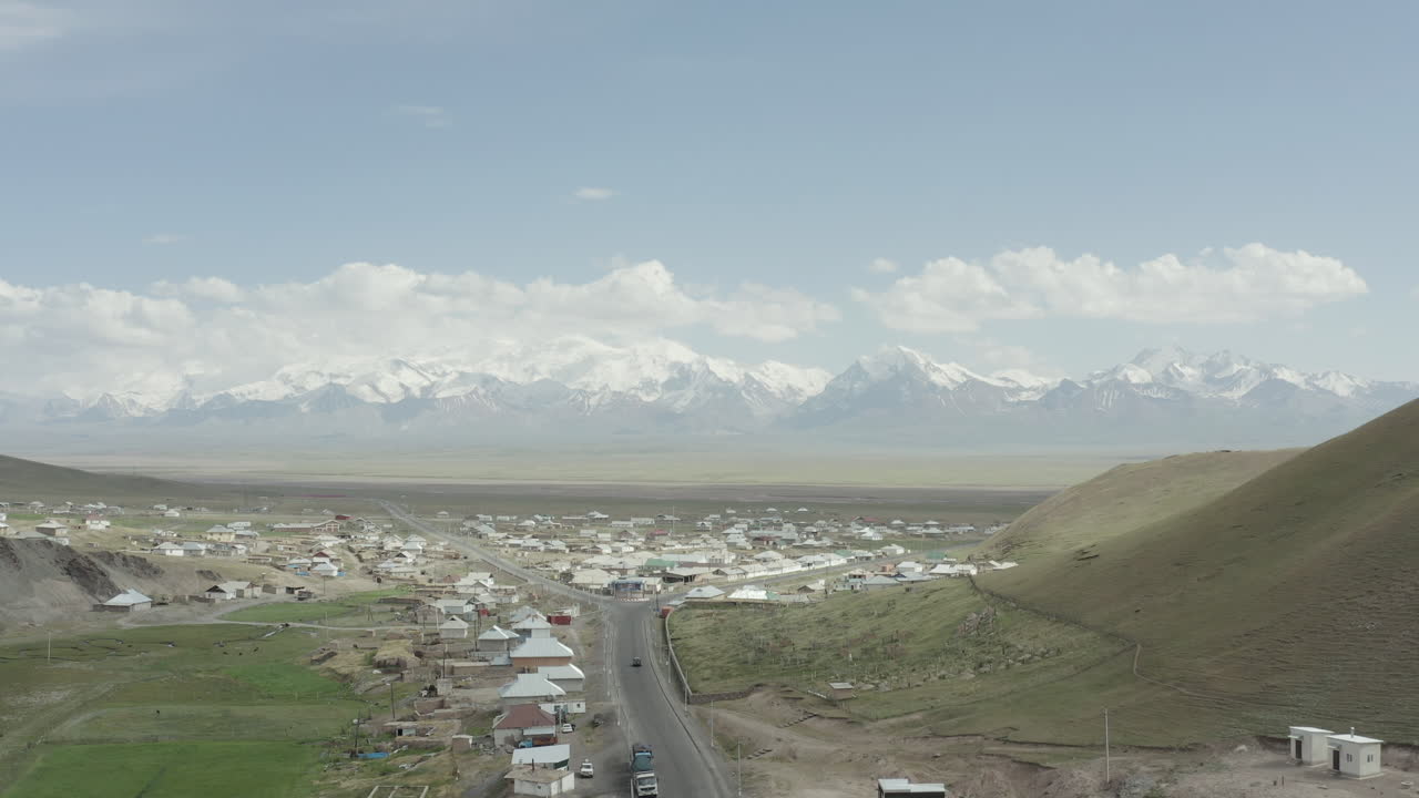 A rural village in kyrgyzstan with snowy mountains in the background, aerial view