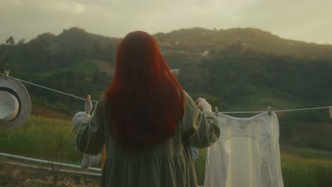 woman drying clothes in the mountains at sunset