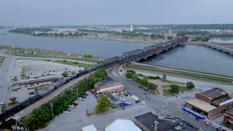 Train-moving-over-Mississippi-River-railroad-bridge-in-Davenport,-Iowa-with-drone-video-moving-in