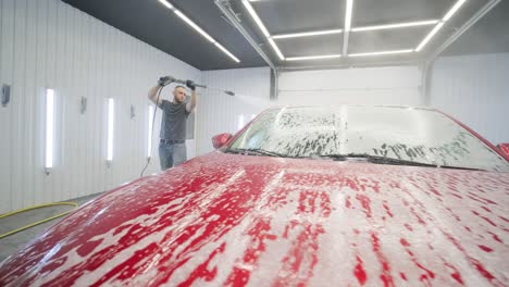 car washing cleaning with foam and high pressured water. red car