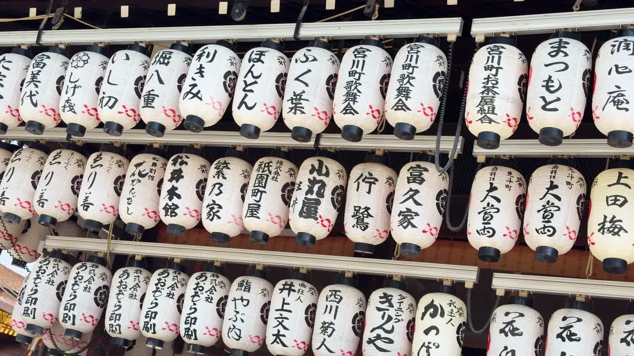 Statisk medium shot af rækker af hvide papirlanterner med sort kanji-kalligrafi i Kyoto