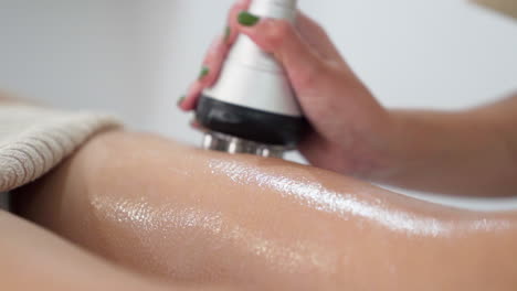 Beautician performing body radiofrequency on the patient&#039;s leg for cellulite reduction and skin firming