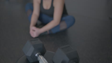 Wide-Rack-Focus-Tilt-Up-of-a-Woman-Stretching-Her-Legs-at-a-Gym