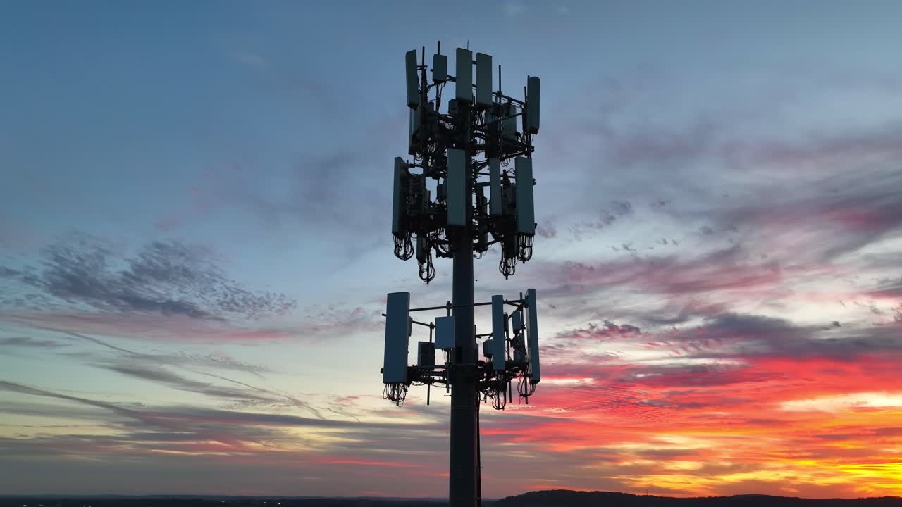 Futuristic cell tower animation. 5G network with wifi, cloud, IoT, and surveillance capabilities. Aerial orbit with colorful sunset in background. Telecommunications, connectivity theme