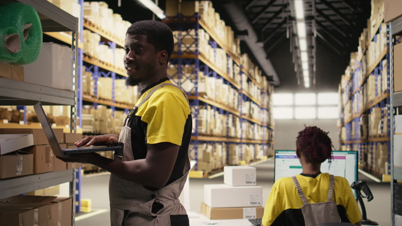 Black male staff verifying inventory pallets in e-commerce logistics center