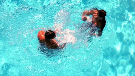 Pareja-Divirtiéndose-Y-Chapoteando-En-La-Piscina