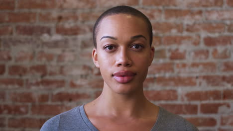 retrato de una mujer afroamericana sonriente de pie contra una pared de ladrillo en una cafetería