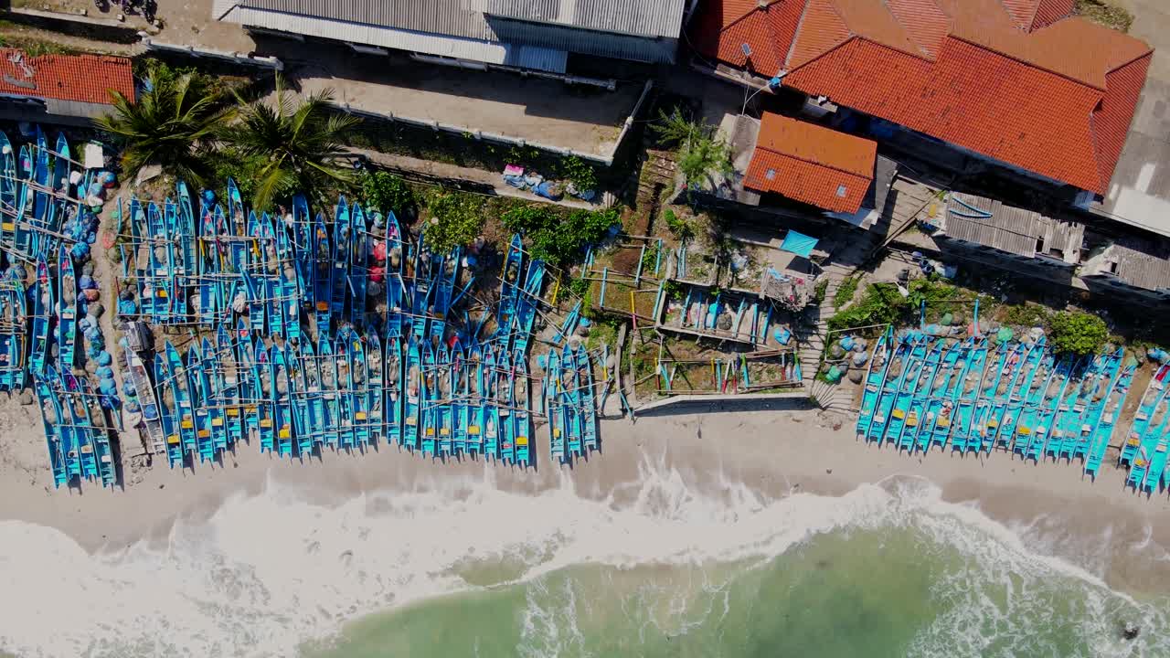 여름 에 인도네시아 해변 에 있는 파란색 보트 들 의 군중 을 보여 주는 위 아래 로 찍은 사진 - 모래 해변 에 도달 하는 파도