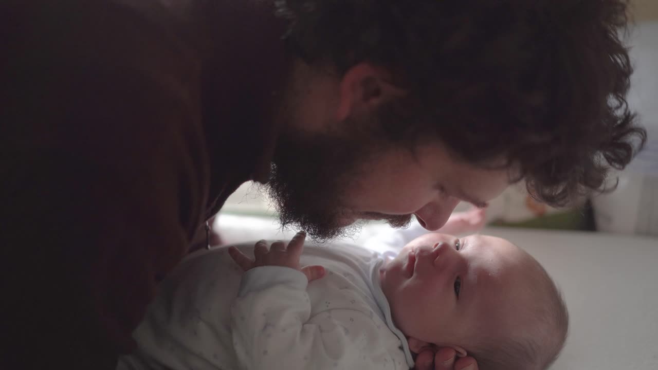 Father interacting with newborn baby at home