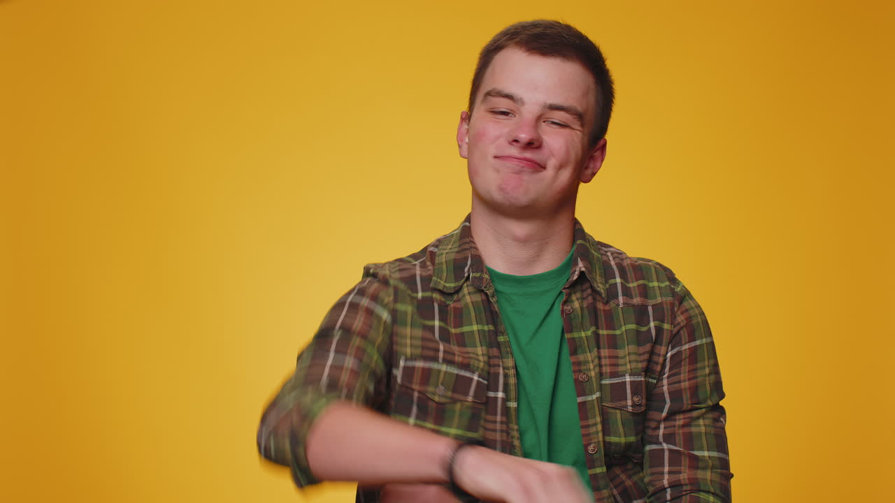 캐주얼 셔츠를 입은 화가 난 젊은 남자가 엄지손가락을 내려놓고 표시 제스처, 불쾌감, 불만을 나타 ⁇ 니다.