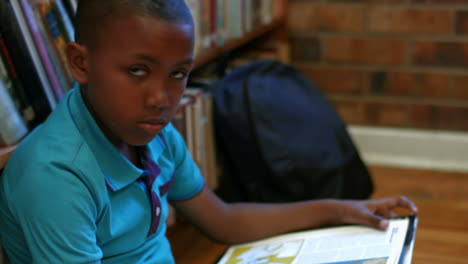 Cute-pupil-reading-on-library-floor