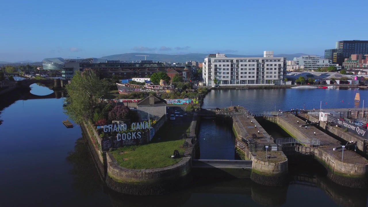 Veduta aerea del Grand Canal a Dublino con numerose chiuse, una nave abbandonata, l'Aviva Stadium, appartamenti e uffici sullo sfondo