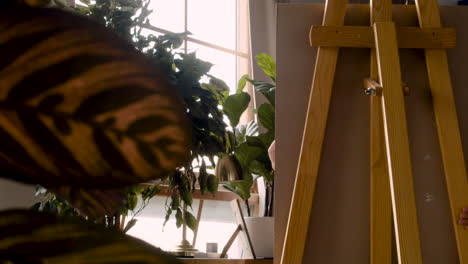 rear view of a lectern and little blonde girl painting on the lectern next to the window at home