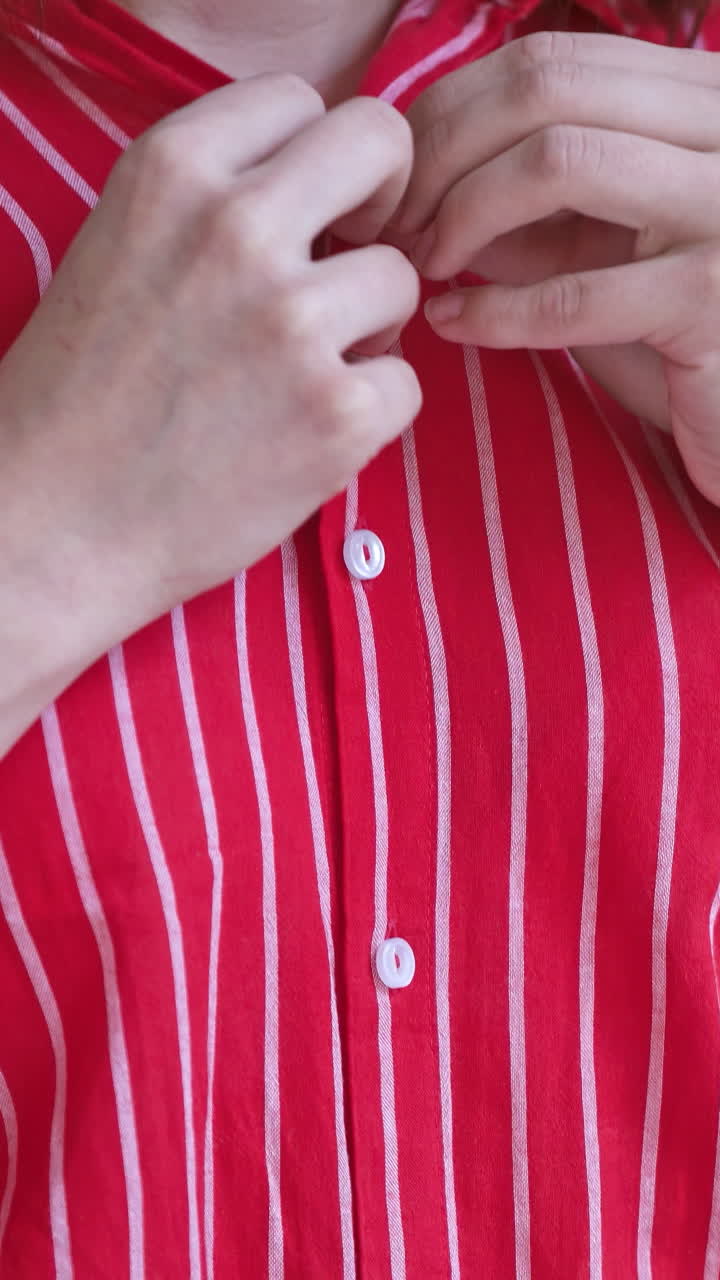 Woman hands buttoning shirt. Stylish woman wearing shirt buttoning button. Vertical video