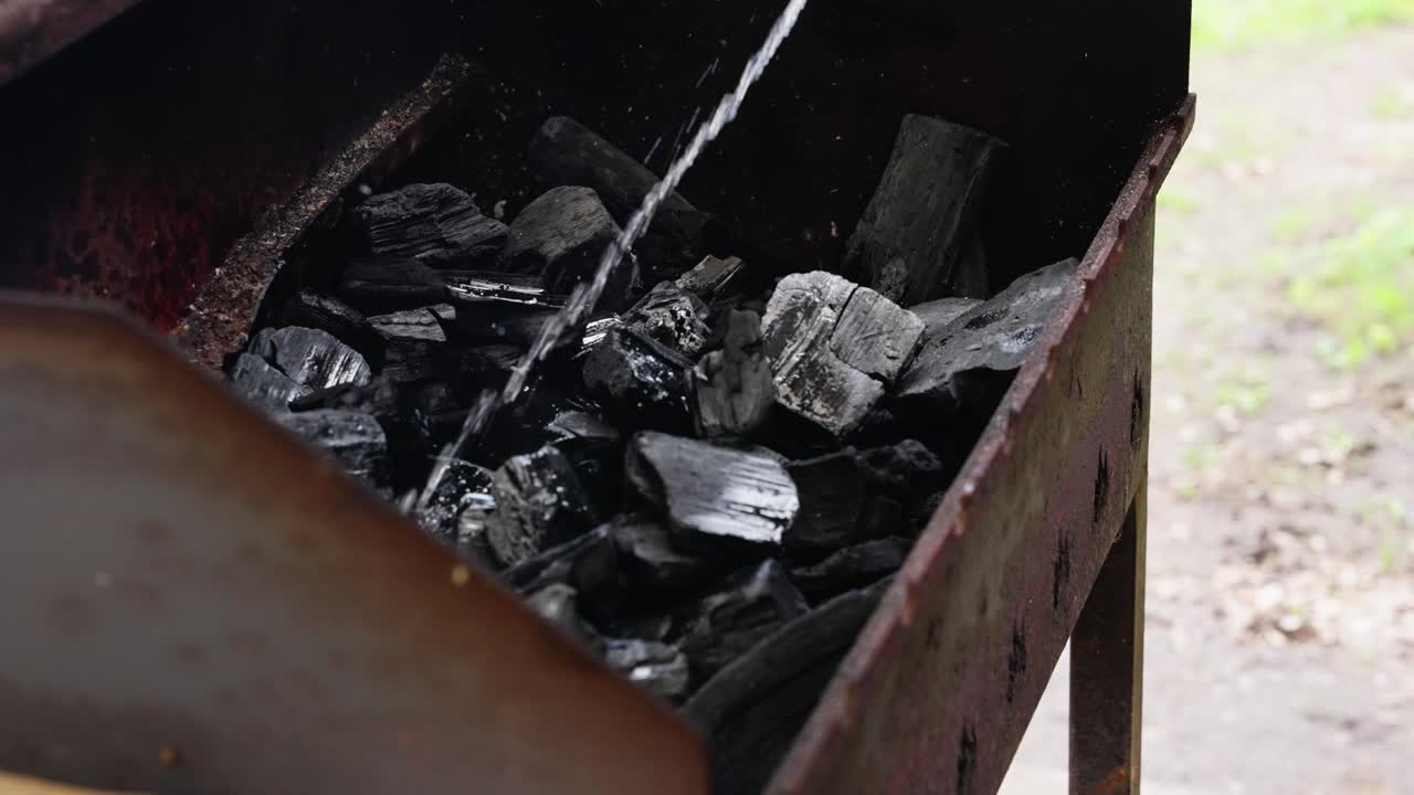Barbecue coals soaked with flammable liquid before ignition in backyard prep