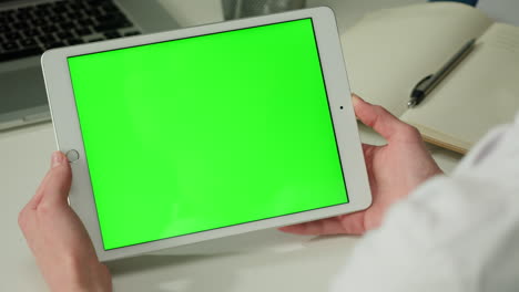 persona que sostiene una tableta con una pantalla verde