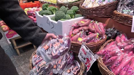 customer selecting produce at a vegetable stand.