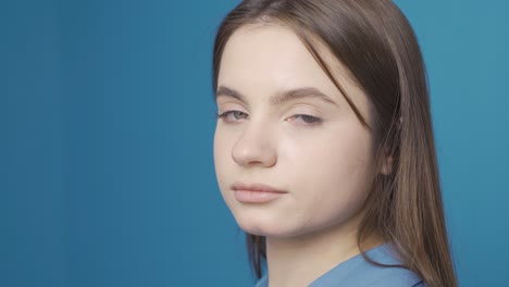 ukrainian young woman looking dull at camera. blue background.