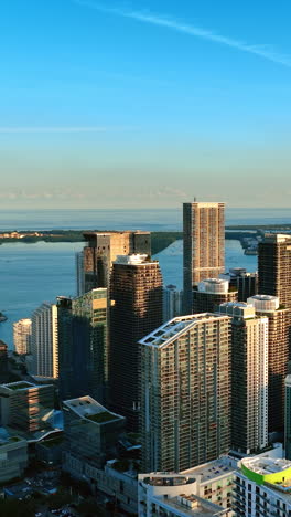 Beautiful skyscrapers in the rays of setting sun. Downtown of Miami, Florida, USA with waterscape at backdrop. Top view. Vertical video