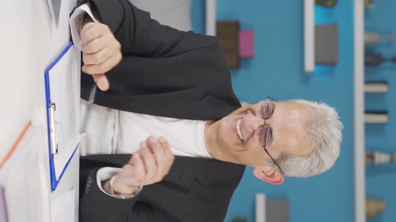 video vertical de un trabajador de oficina en casa leyendo buenas noticias y sintiéndose feliz.