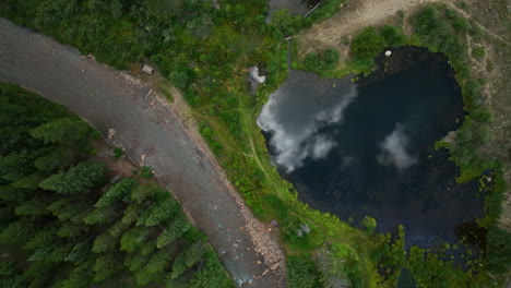 Birds-Eye-view-pond-lake-mirror-reflection-clouds-aerial-cinematic-drone-Keystone-Blue-River-ski-resort-summer-Breckenridge-Colorado-Vail-resort-Epic-Pass-ski-snowboard-bike-biking-slowly-up-motion