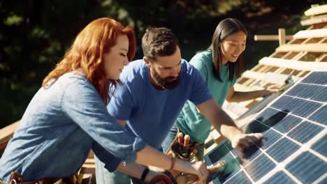 a team of three individuals installs solar panels on a rooftop during a sunny day. their focused teamwork highlights the growing trend of renewable energy solutions.