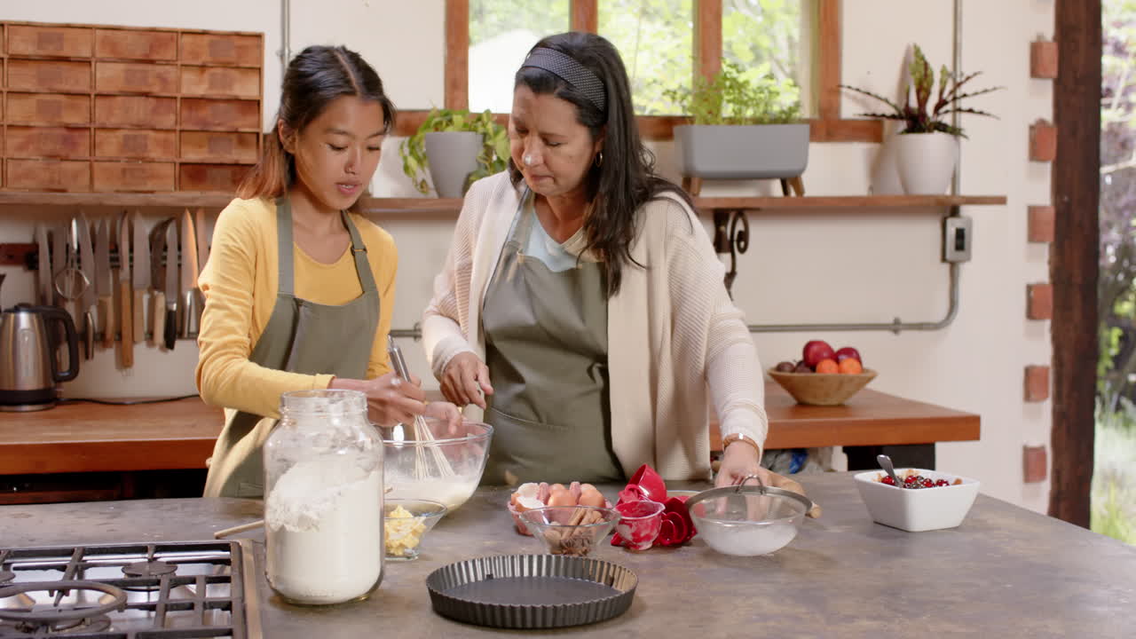 Di dapur yang nyaman, wanita muda multiras dan nenek memanggang bersama, di rumah.