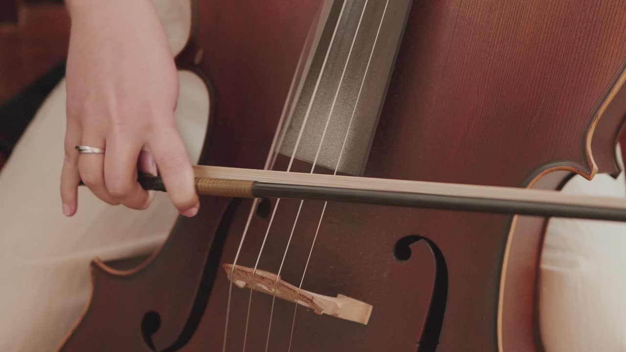 close up of cello being played with bow showing fine wood texture and elegant sound holes