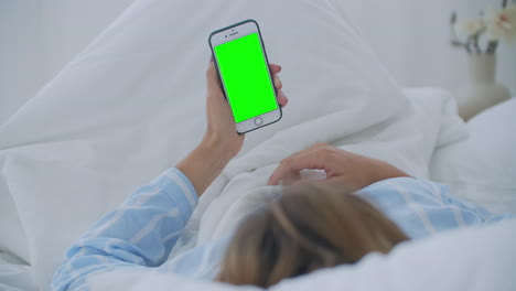 Junge-Frau-Mit-Handy-Auf-Dem-Bett,-Schulteransicht.-Technologiesucht.-Greenscreen-Telefon.-Junge-Frau-Berührt-Bauch-Und-Benutzt-Smartphone-Im-Schlafzimmer