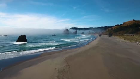 aerial: flyover of an oregon beach as waves crash into the sand