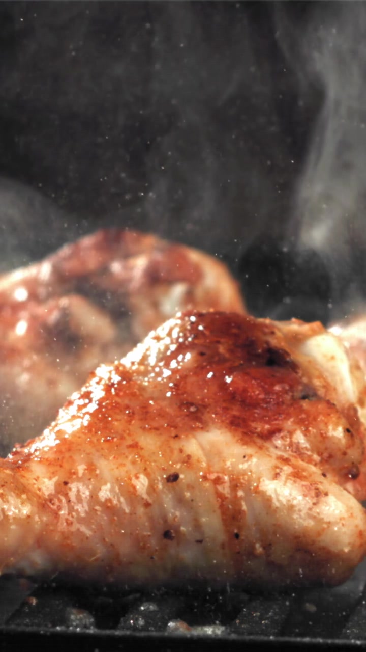 Deliziose ali di pollo in cottura su una griglia rovente con fumo