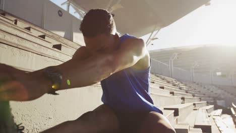 atleta afroamericano estirándose en el estadio