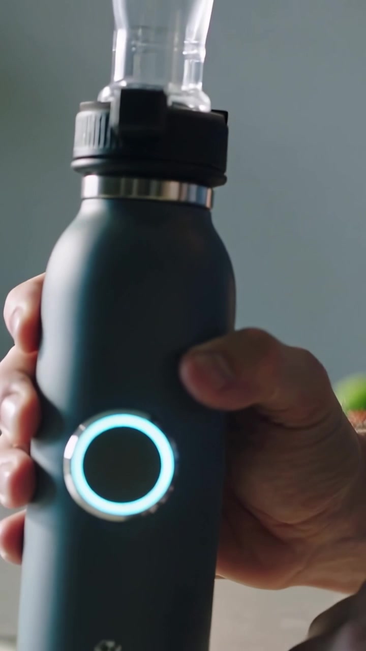Video verticale: Una mano prende e ruota una borraccia opaca sul bancone della cucina, mostrando un anello LED.