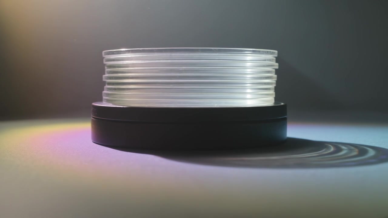 Luce che si sposta dall'alto a sinistra proiettando anelli a coste sulla base su un tavolo, creando bande prismatiche per lo studio.
