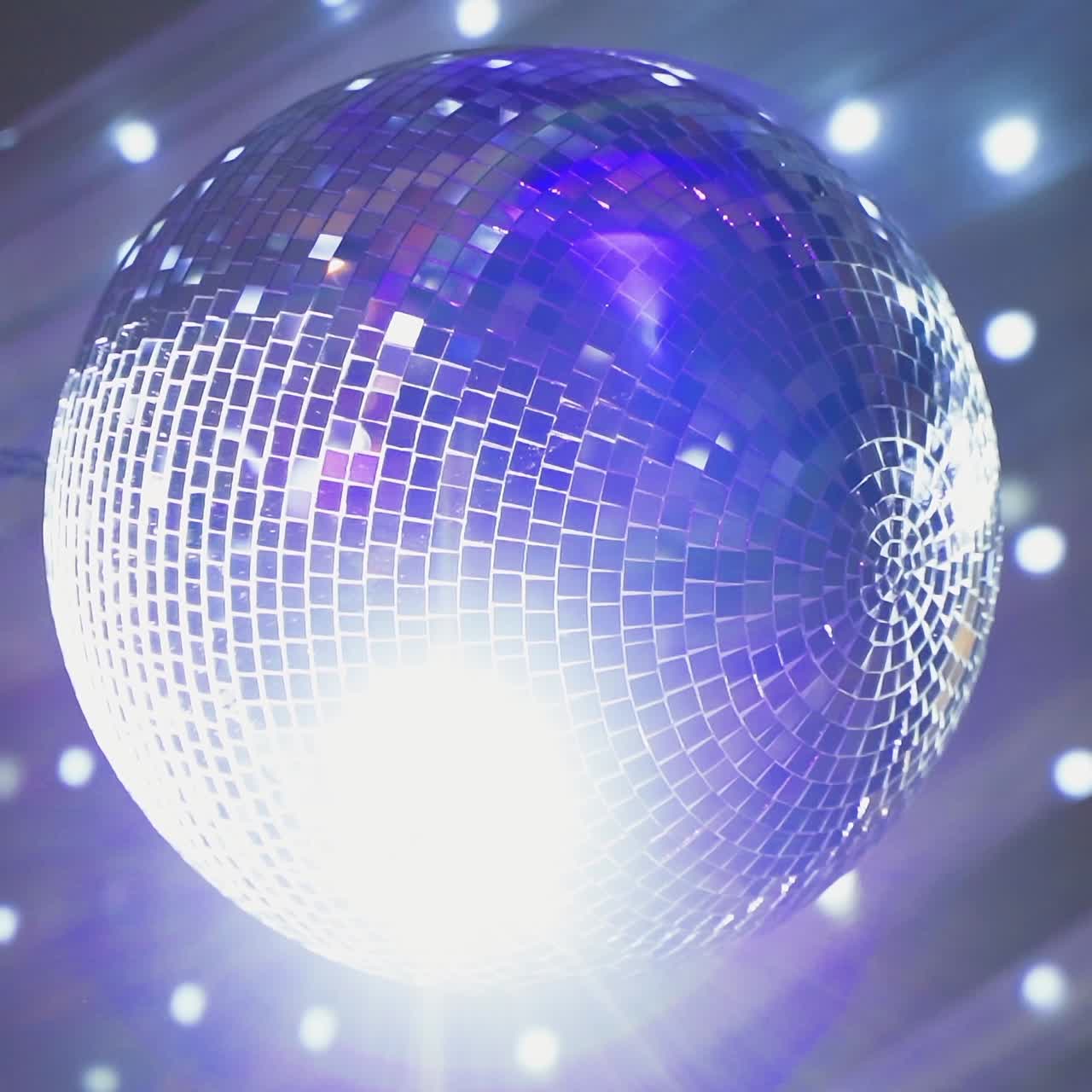 Round mirror ball shimmering. Shining disco ball hanging on the ceiling and rotating at nightclub. Close-up.