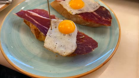 Traditional-Spanish-tapas-with-Jamon-Iberico-and-quail-eggs-on-bread-in-a-restaurant,-Iberian-ham-in-Marbella-Malaga-Spain,-4K-shot