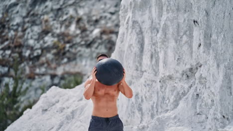 man exercising medicine ball outdoors. healthy young man exercising with medicine ball