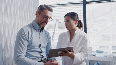 female doctor showing mature male patient test results on digital tablet in office