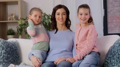 Happy-Mother-and-Two-Daughters-Kissing-Her-at-Home.people,-family-and-love-concept-two-daughters-kissing-happy-mother-at-home