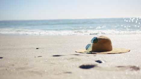un sombrero de paja y gafas de sol descansan en una playa soleada con espacio de copia