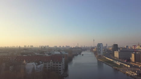 Spree-River-with-Berlin-Cityscape-and-riverside-in-Sunset-Golden-Hour,-Aerial-wide-angle-forward-dolly-in-shot