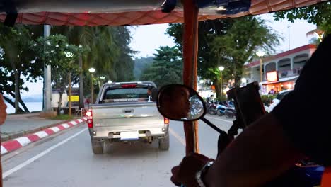 un tuk-tuk sigue a un camión en krabi