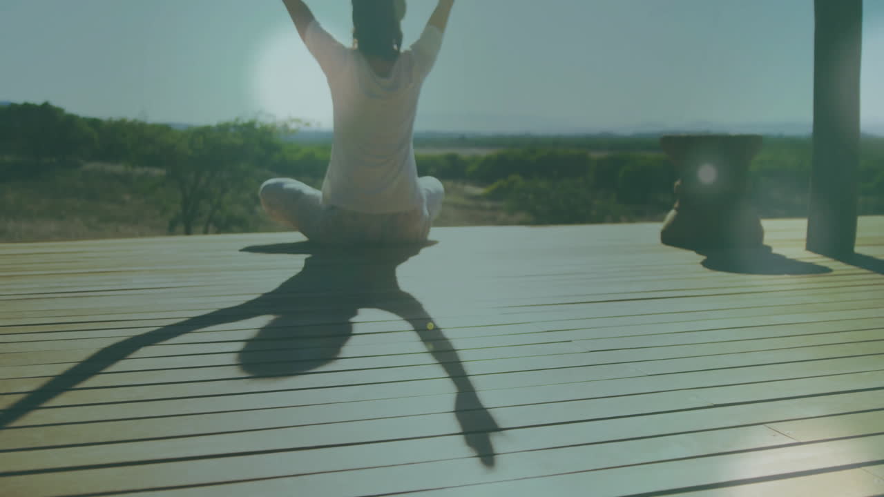 Animation of light spots over caucasian woman practicing yoga at home
