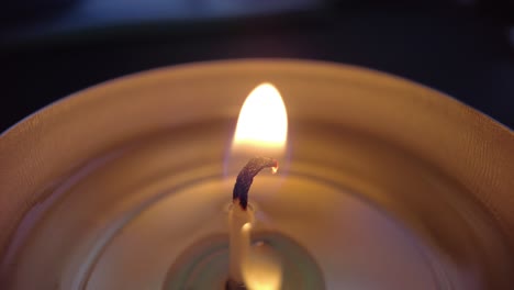 flame close up macro shot of a tea light burning wick against a black background