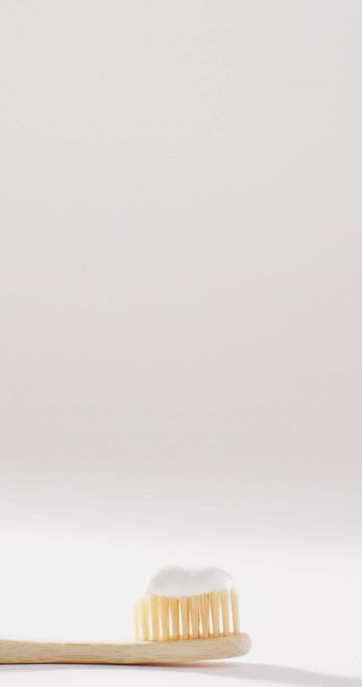 Vertical video of toothbrush with paste on white background with copy space