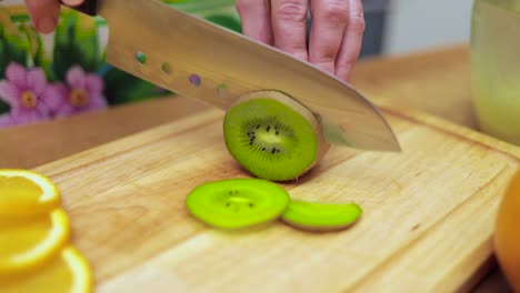 women's hands housewives cut with a knife fresh kiwi on the cutting board of the kitchen table