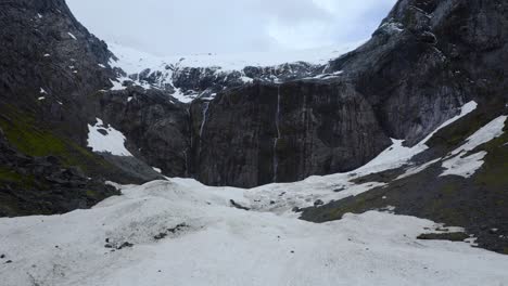 Serene-aerial-above-icy-expanse,-gazing-upon-the-majestic-mountain-cliff-in-Fiordland,-New-Zealand,-South-Island