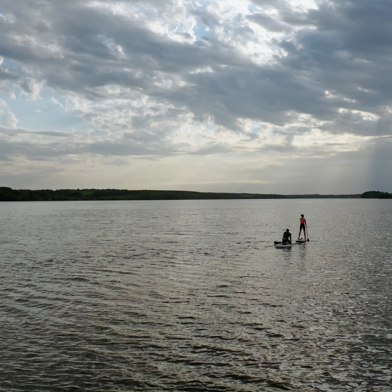 Sailing on boats at dusk. Young people travelling on water on special boards with oars in the middle of a river. Active lifestyle